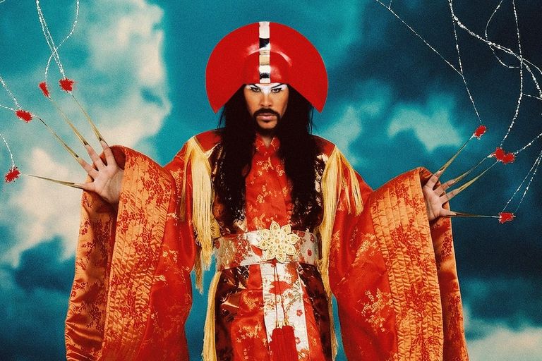 Luke Steele of Empire of the Sun in an ornate red and gold robe with an avant-garde headpiece and long fingernail extensions.